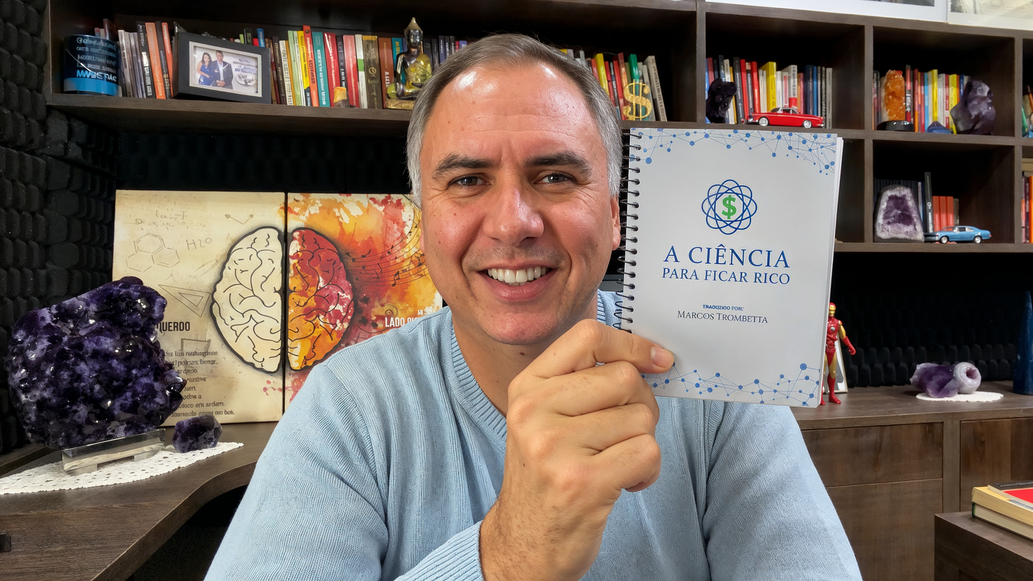 Marcos Trombetta sorrindo, segurando o ebook A Ciência Para Ficar Rico